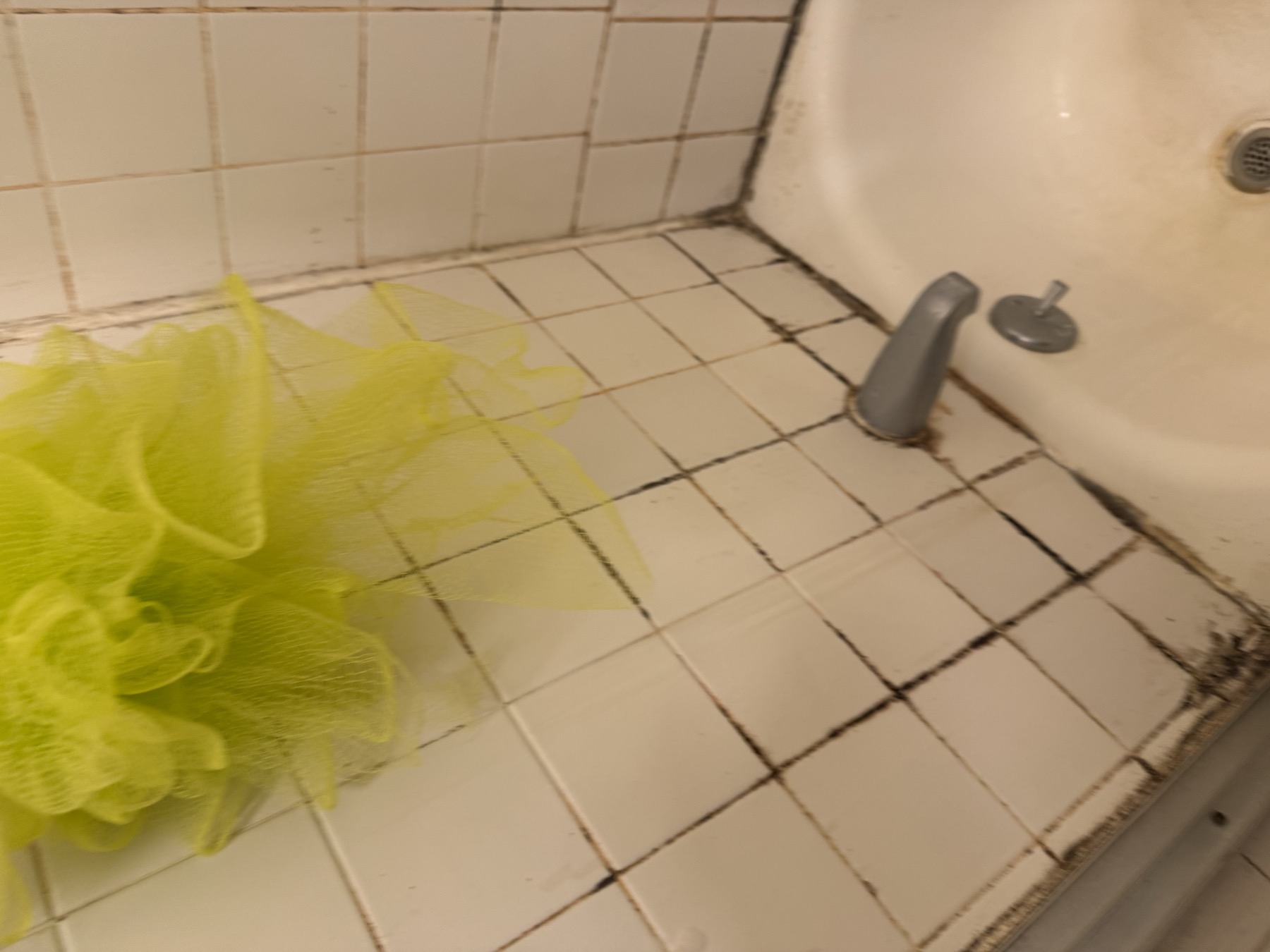 Bathroom shower tile with heavy buildup and visible surface mold or mildew before detail cleaning