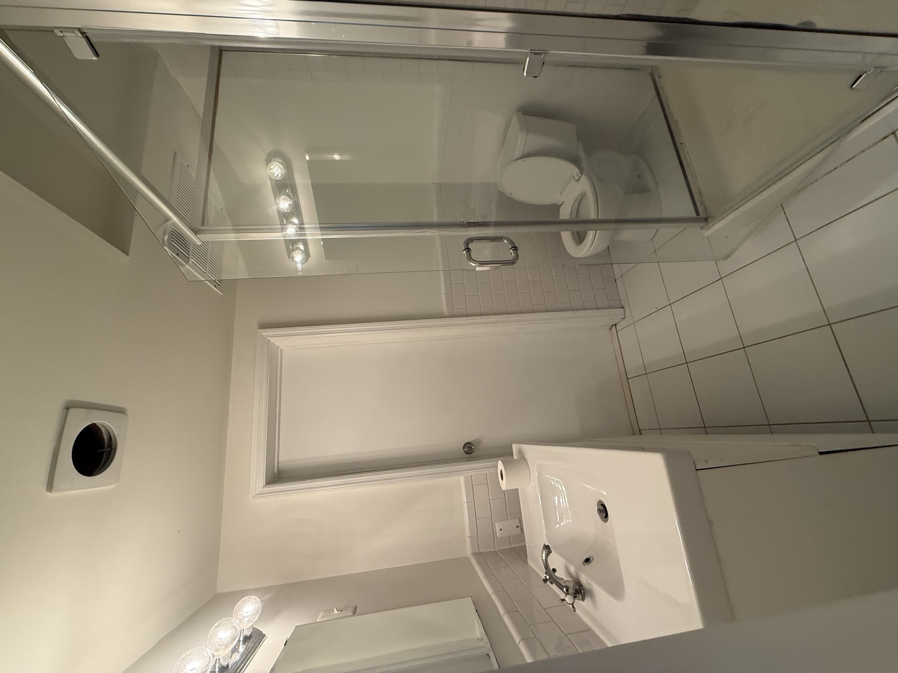 Clean glass shower, sink, toilet, and tiled floor after move-in cleaning