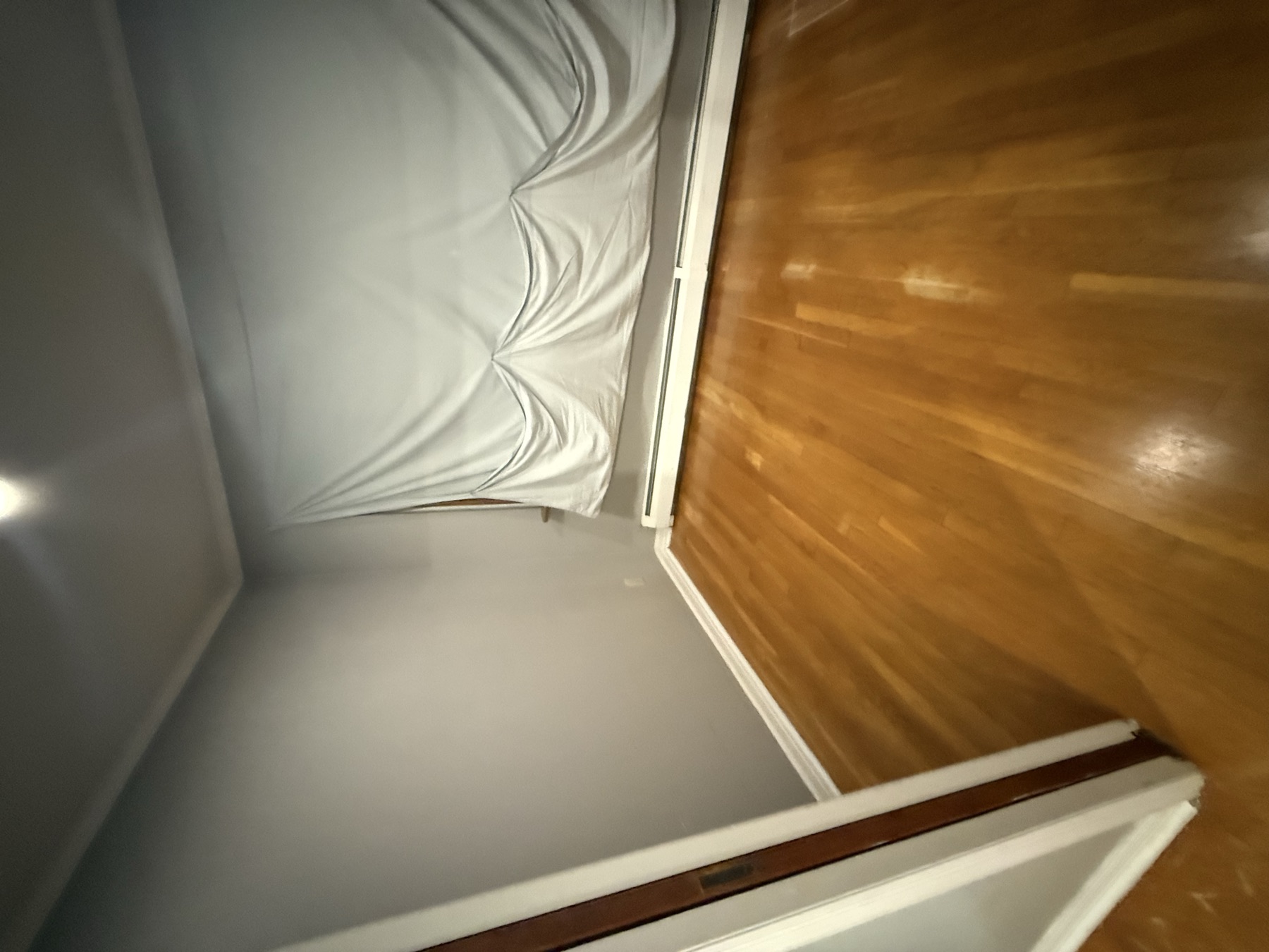 Clean empty bedroom with polished hardwood floor prepared for a property listing